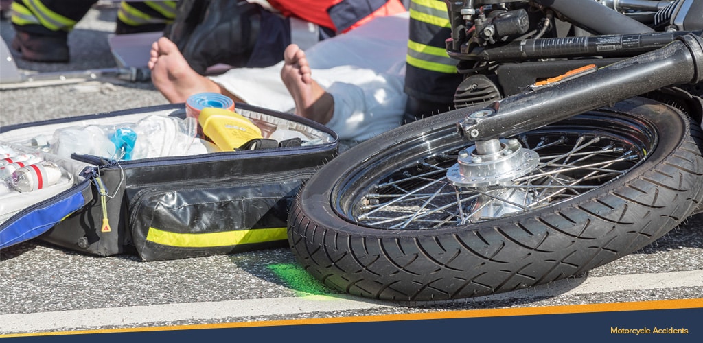 Motorcycle laying on the ground on it's side while paramedics tend to the injured driver, Motorcycle Accidents.