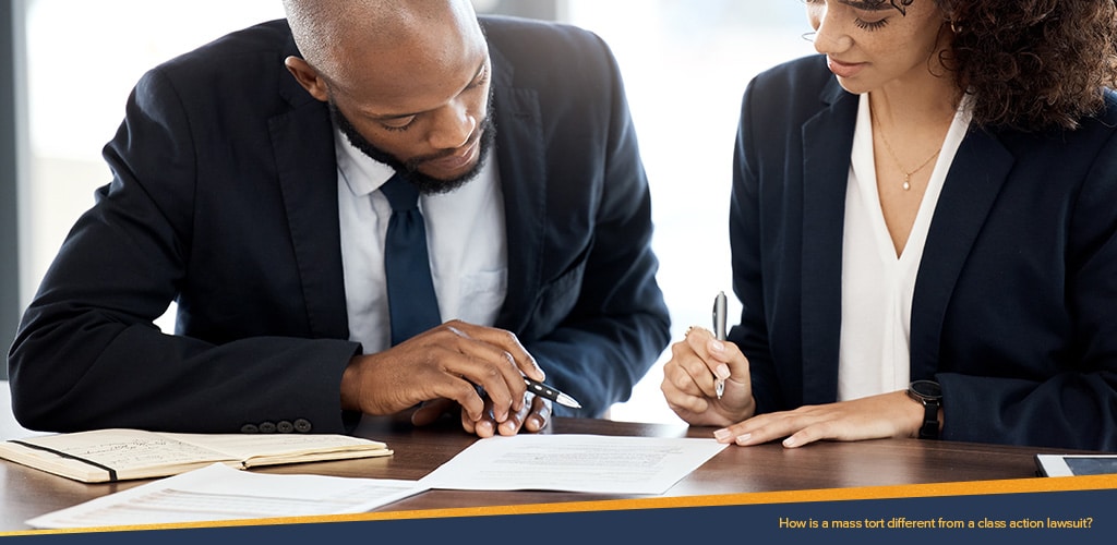 How is a mass torn different from a class action lawsuit? Man and woman signing documents.